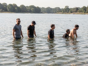 Men standing in body of water, photo
