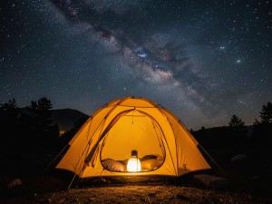 Lighted lamp in yellow dome tent under milky way, photo