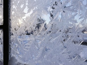 Frosted window pane with intricate ice crystal formations in winter