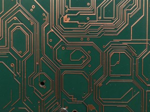 Tech circuit board pathways forming a hexagonal grid pattern on a dark green substrate with copper traces, photo