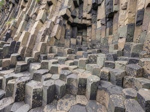 Interlocking hexagonal basalt columns forming a geometric cliff face, photo