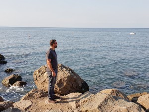 Man standing near rock viewing calm sea, photo