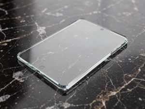 Clear glass tablet resting on a polished dark stone surface, photo